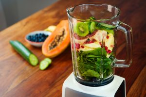 Fruits and vegetables as ingredients for a healthy smoothie: papaya, figs, blueberries, pomegranate seeds, raspberries, pineapple, cucumber, kiwi and baby spinach