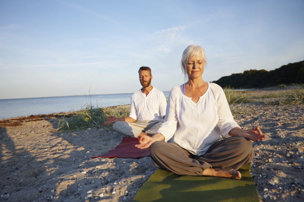 Paar meditiert am Strand - Yoga und Ayurveda zum Abnehmen