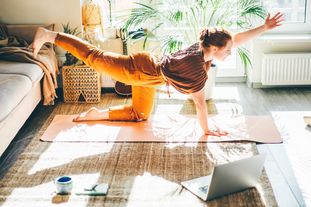 Junge Frau macht Yoga zu Hause - Yoga und Bewegung gegen Migräne