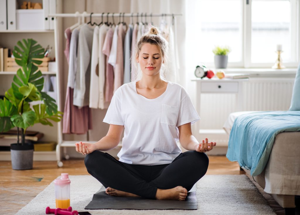 Eine Frau macht Yoga im eigenen Schlafzimmer.