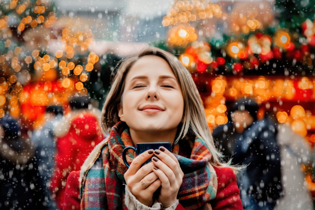 Mädchen trinkt Glühwein auf dem Weihnachtsmarkt