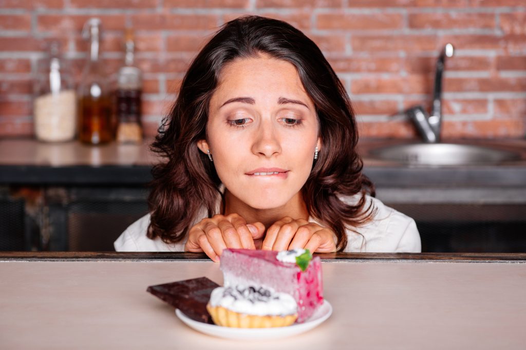 Eine Frau schaut gierig auf Kuchenstücke.