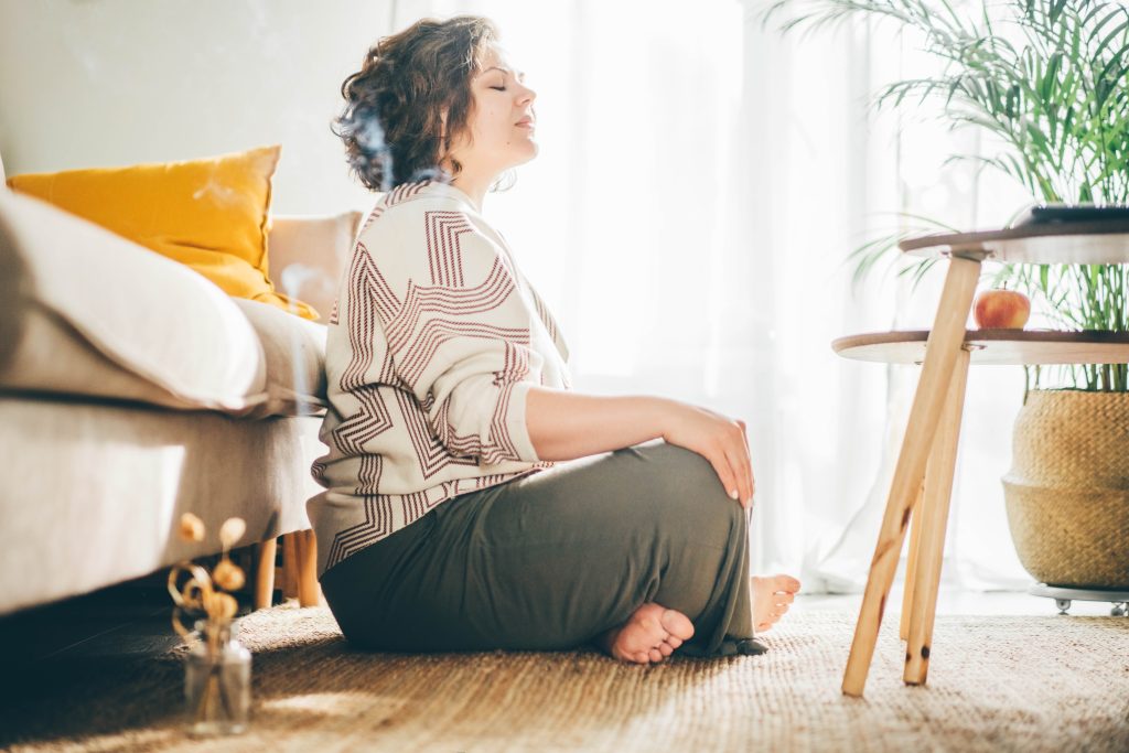 Eine Frau meditiert im eigenen Wohnzimmer