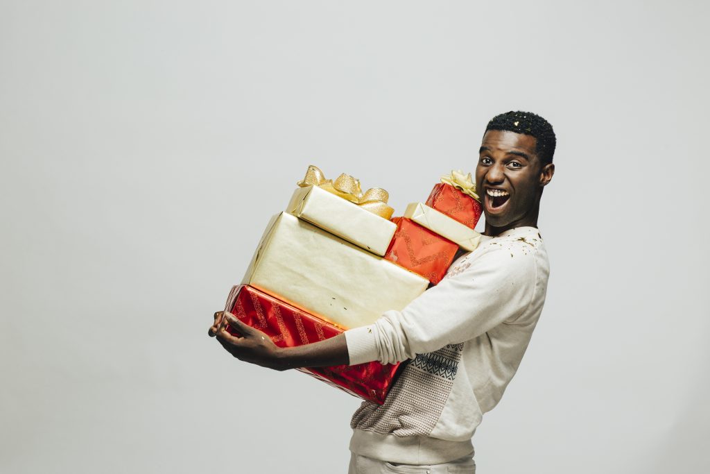 Mann lachend mit vielen Geschenken auf dem Arm