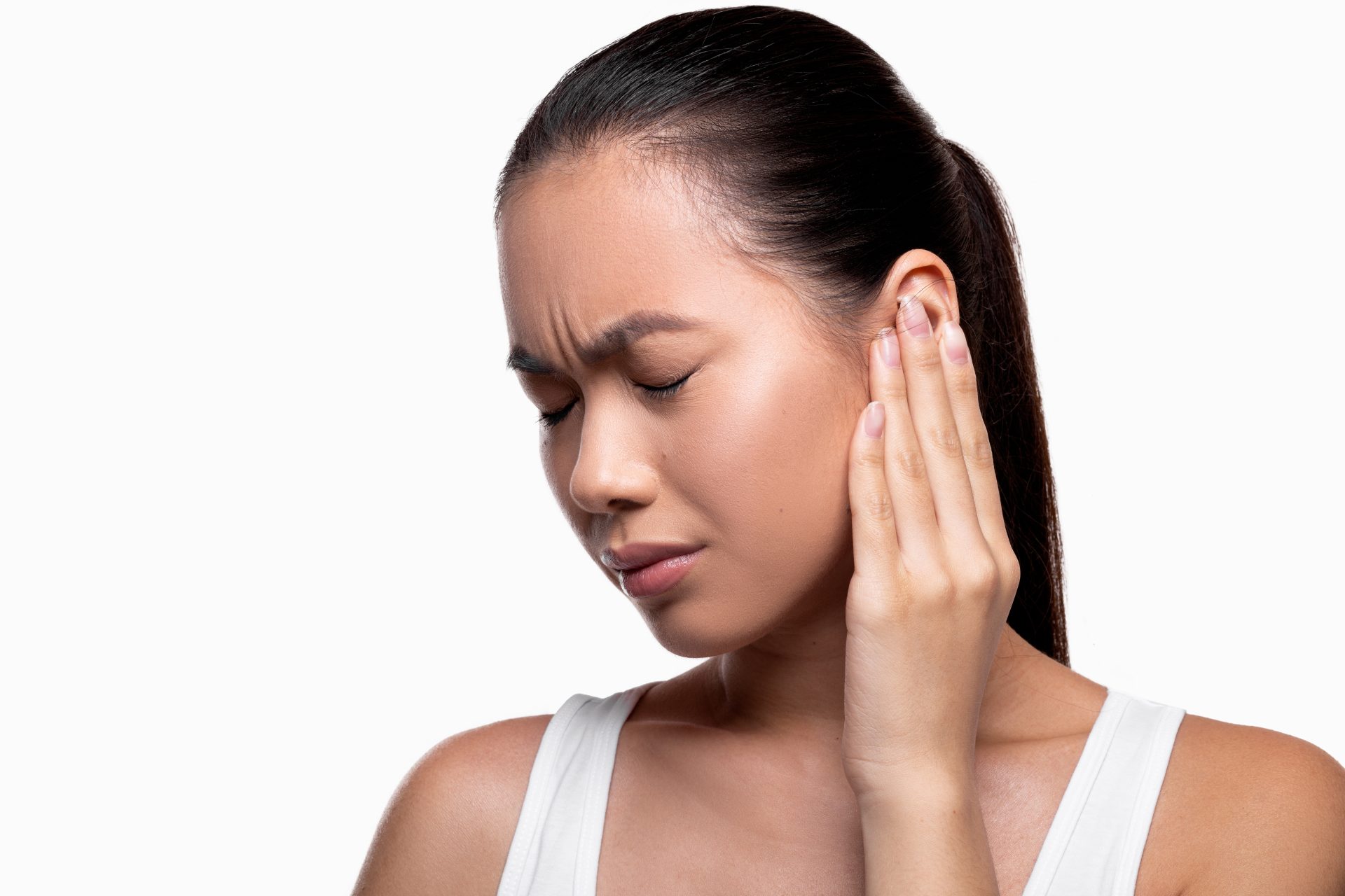 Frau mit Tinnitus hält sich schmerzerfüllt ihr Ohr