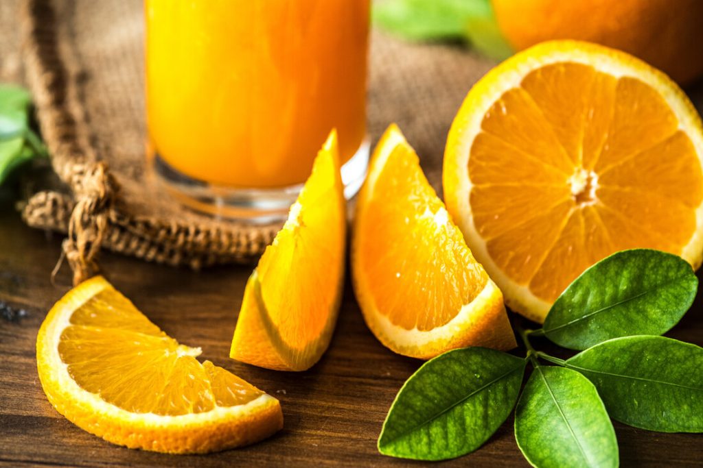 Orangensaft und aufgeschnittene Orangen