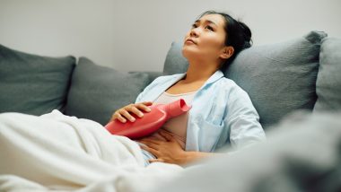 Frau mit Wärmflasche hat Bauchschmerzen