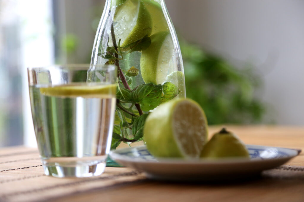 Wasserglas mit Zitrone und Zitrone auf einem Teller.  