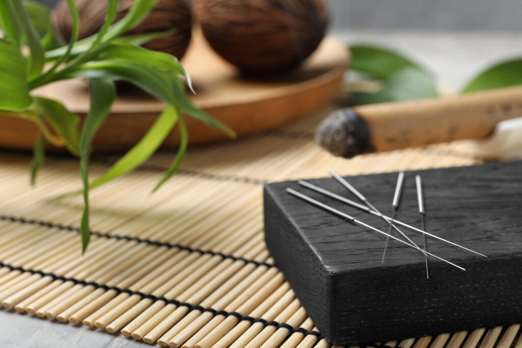 Akupunkturnadeln auf einem Brett auf einer Bambusmatte