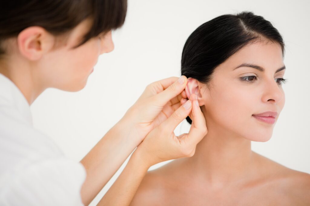 Eine junge Frau bekommt eine Akupunkturnadel am Ohr gesetzt, um abzunehmen