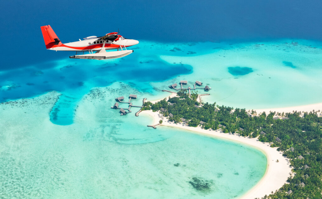 Eine weiter top Sehenswürdigkeit auf den Malediven ist ein Ausflug mti dem Wasserflugzeug, das türkisfarbene Lagunen an einer maledivischen Insel überfliegt 