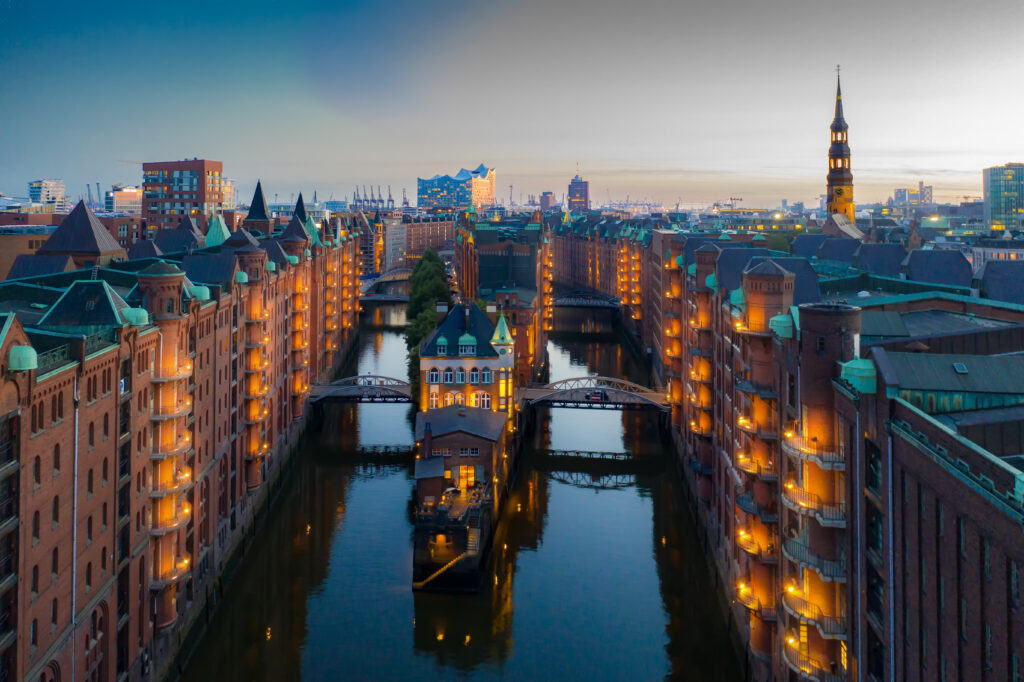 Die beleuchteten Lagerhäuser der Speicherstadt und ihre Kanäle in der Hamburger Abenddämmerung 