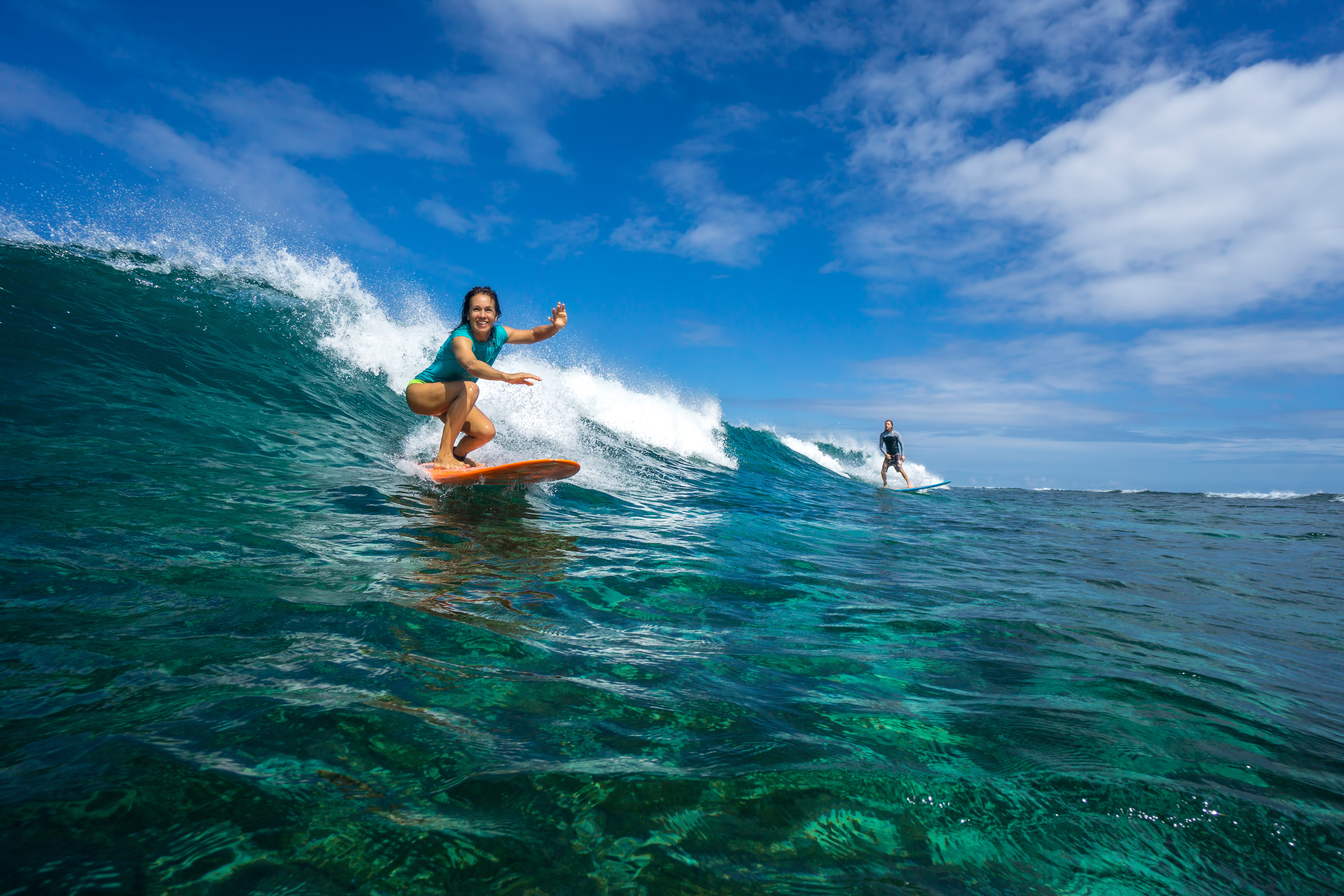 Surfer, die eine Welle reiten. Ein Ritt mit dem Surfbrett gehört zu den top 12 Sehenswürdigkeiten auf den Malediven.