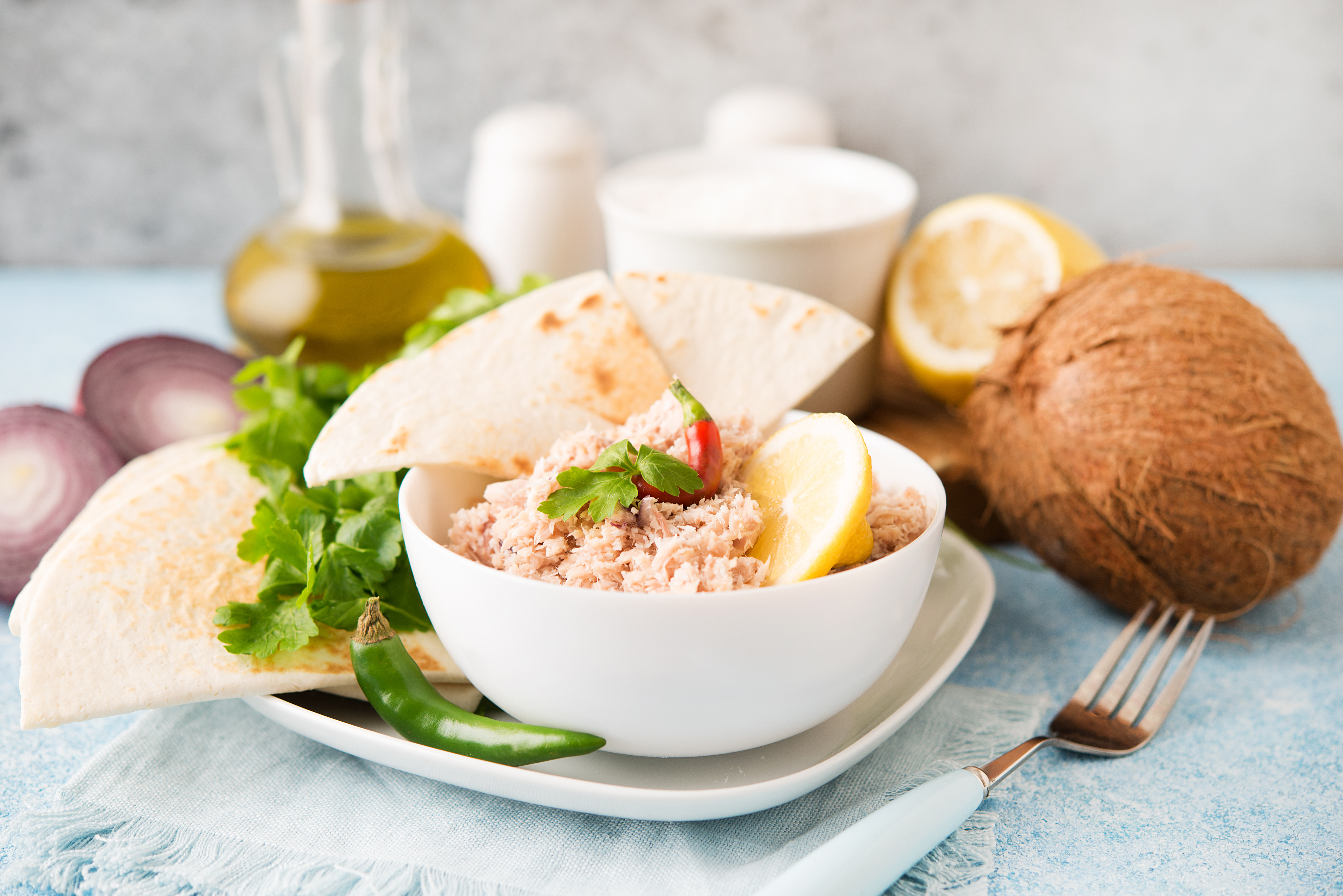 Traditionelles Gericht mit Fisch, Zitrone, Gewürzen und Brot, im Hintergrund ist eine Kokosnuss