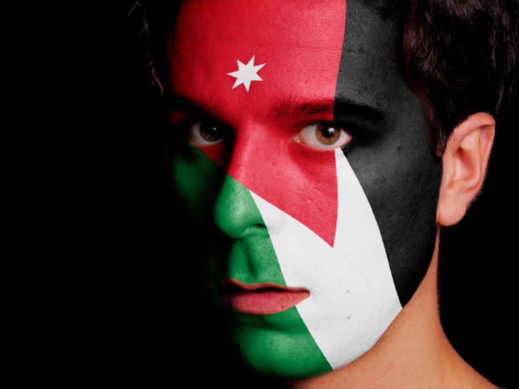 Die jordanische Flagge auf dem Gesicht eines jungen Mannes gemalt