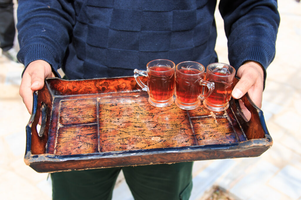 Ein gastfreundlicher Jordanier bietet Tee auf einem Tablet an.