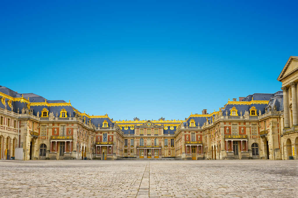Der Eingangsbereich des majestätischen Schlosses Versailles, mit m goldenen Verzierungen auf dem Dach 
