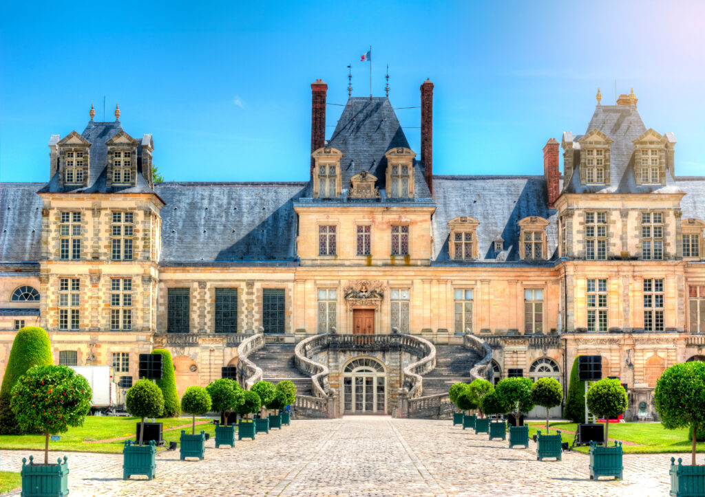 Ein Ausschnitt des Eingangs vom Schloss Fontainebleau, zwei geschwungene Treppen führen zur Eingangstür der Sehenswürdigkeit