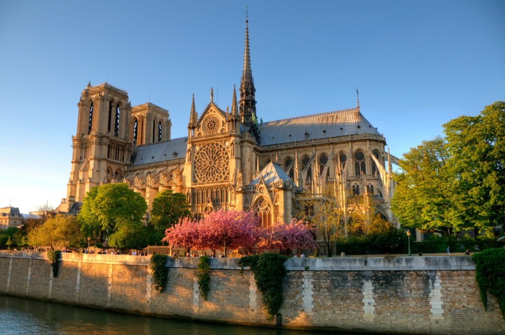 Die Kathedrale Notre-Dame de Paris am Ufer der Seine, mit zwei symmetrischen Türmen auf der linken Seite und einem höheren Kirchturm in der Mitte des Dachs 