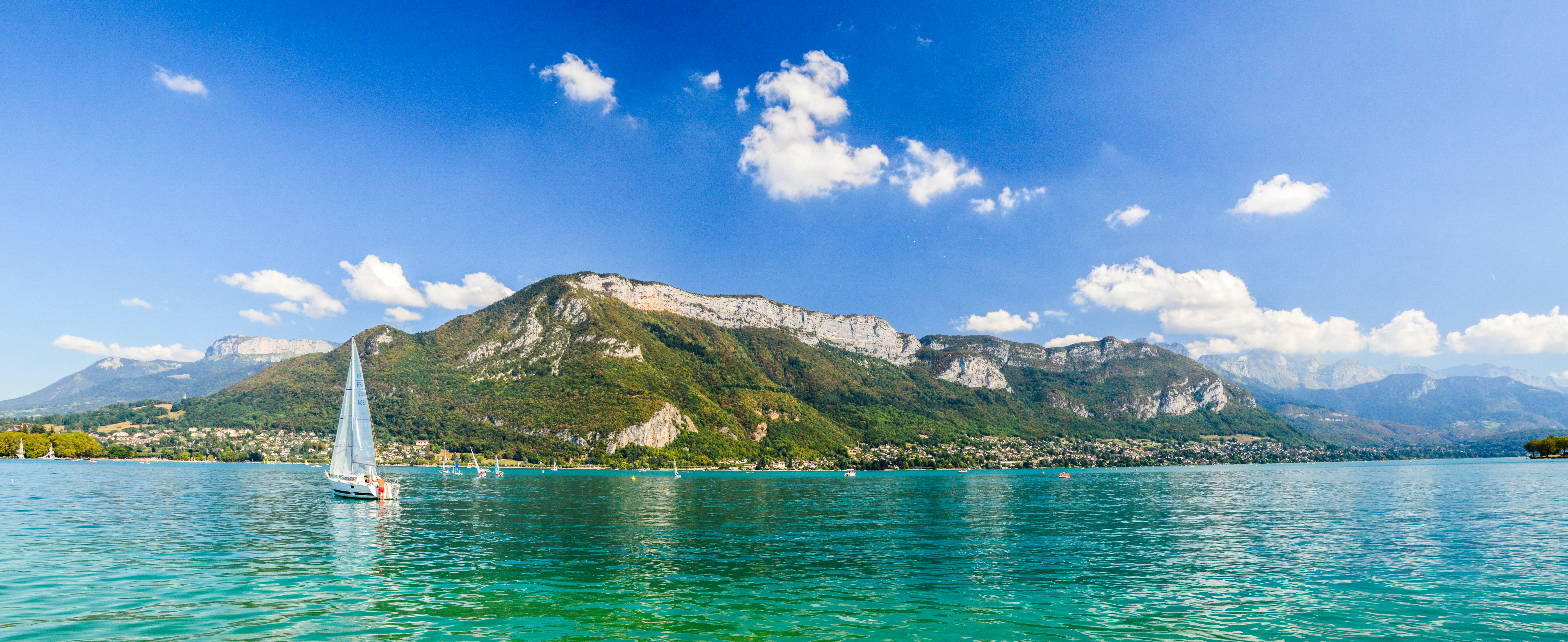 Ein Segelboot auf dem klaren Wasser des Lac d'Annecy, Berge im Hintergrund