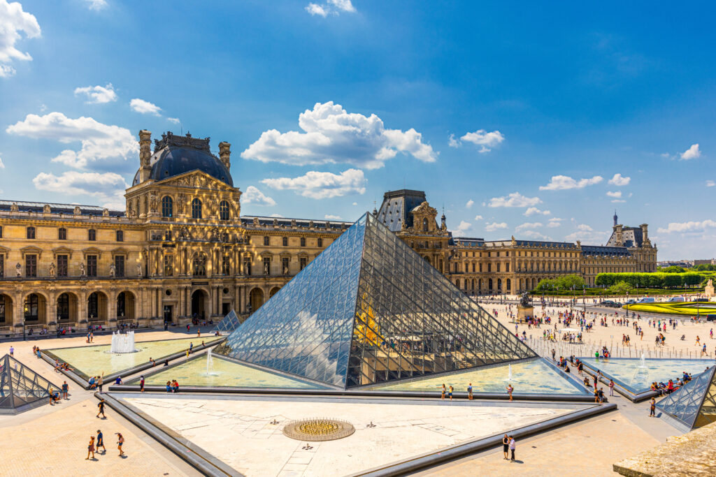 Der Vorplatz des Palasts des Louvre mit der gläsernen Pyramide und vielen Menschen