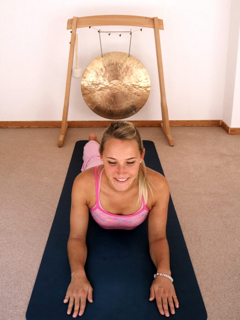 Frau in der Sphinx Yoga-Position, auf den Unterarmen abgestützt und in der Rückbeuge, Unterkörper auf dem Boden