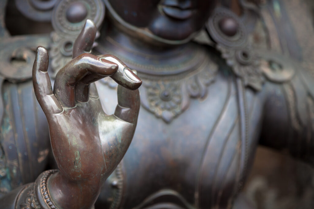 Die Buddha Statue führt die Karana Mudra aus.