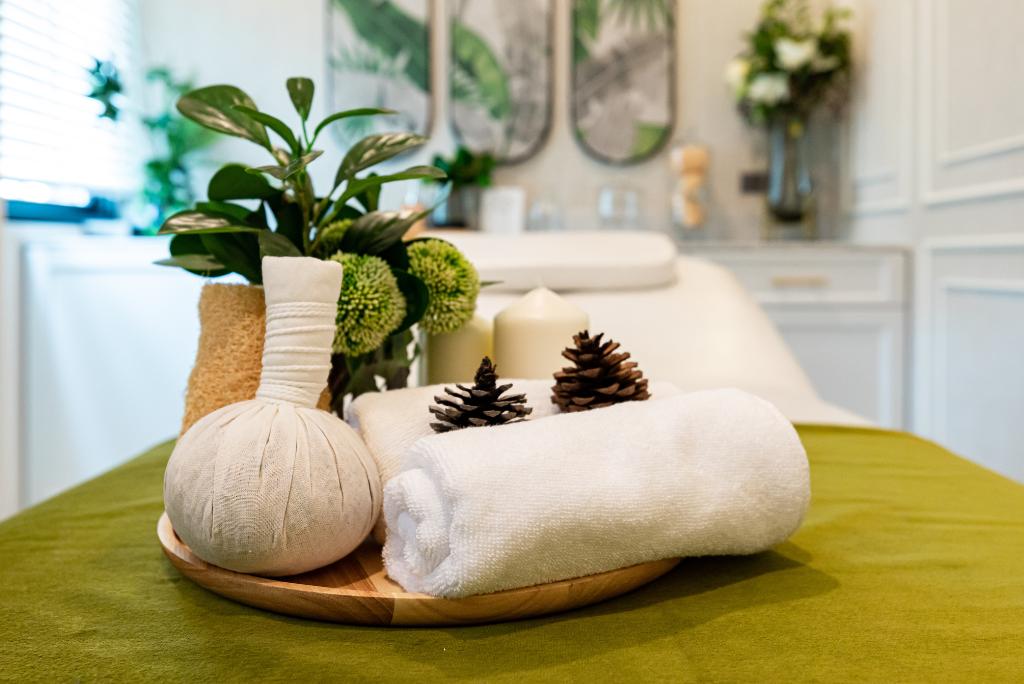 Ein Tablett mit Kräuterstempeln und Tüchern auf einer Massageliege