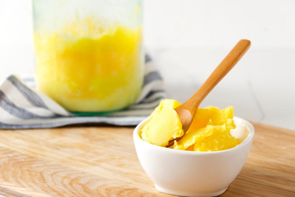 Eine Schale mit Ghee mit Holzlöffel darin