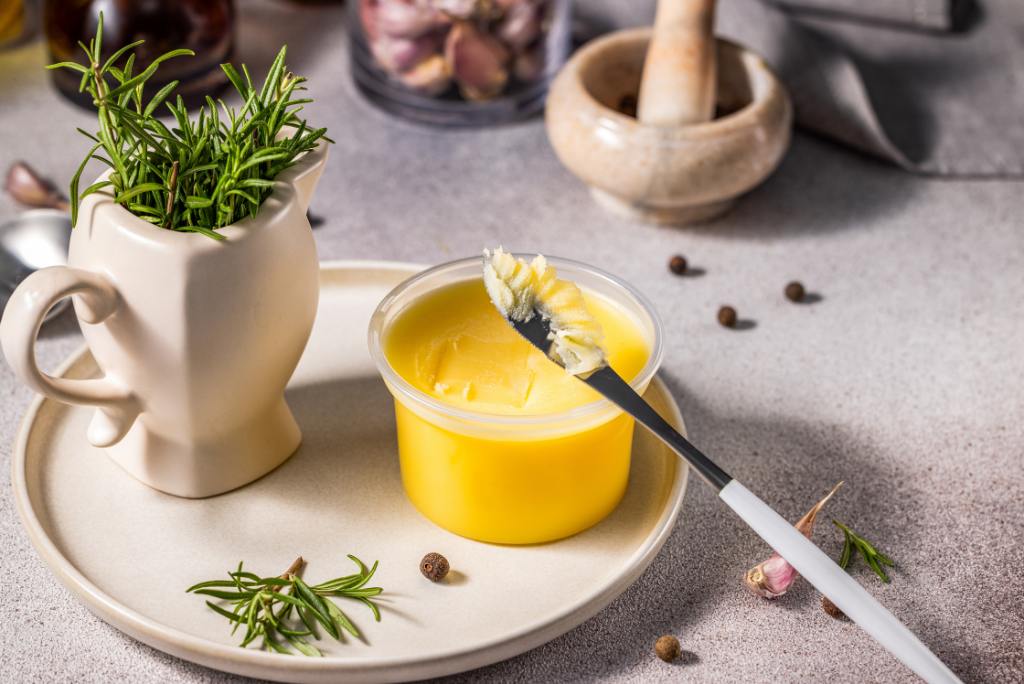Eine Schale Ghee und eine Vase mit Rosmarinzweigen