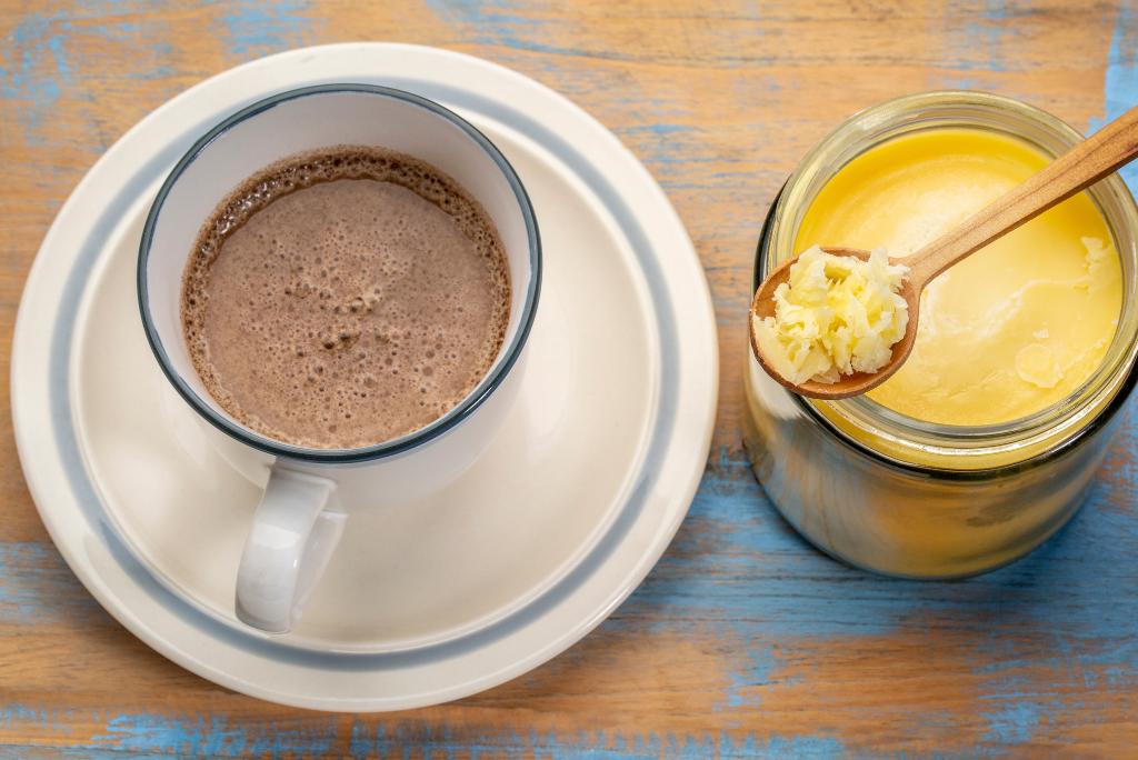 Eine Tasse Kaffee und ein Glas Ghee mit einem Löffel darauf