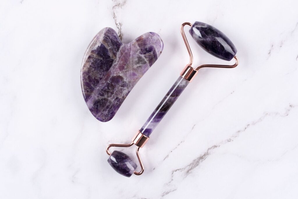 Eine Gua Sha Stein und ein Gesichtsroller aus Amethyst