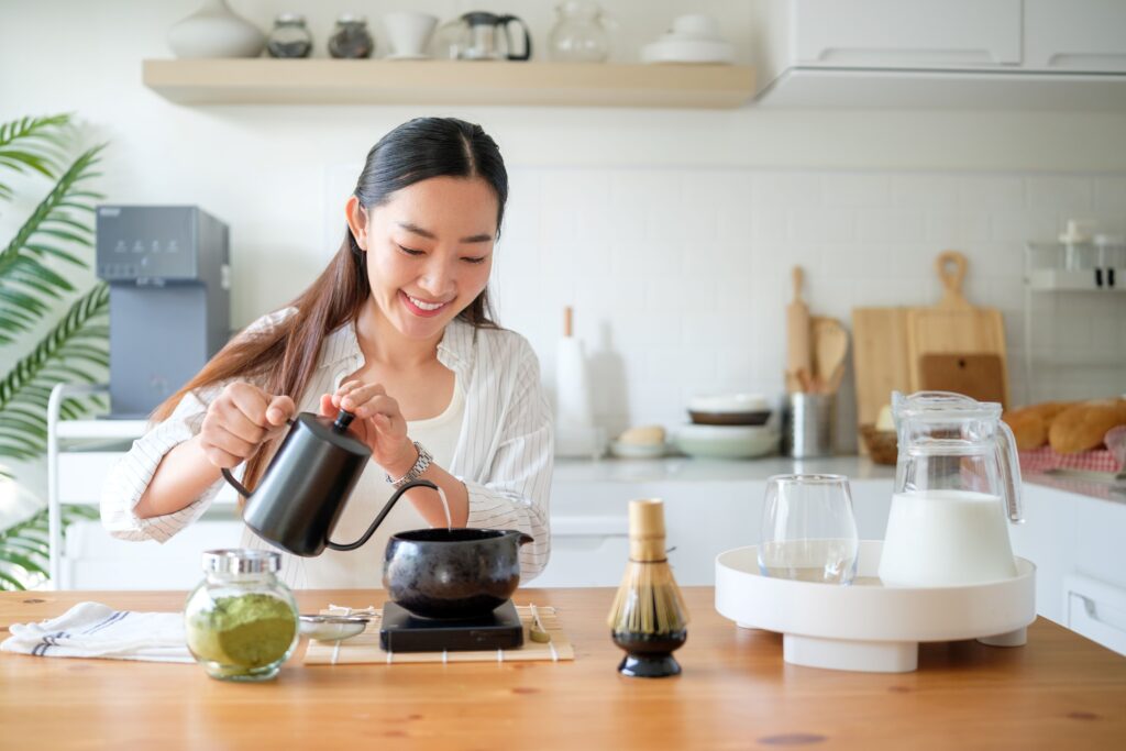 Eine glückliche Frau bereitet sich Matcha zu