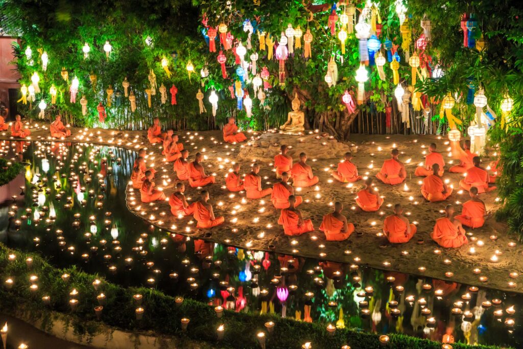 Buddhistische Mönche meditieren an einem Schrein mit vielen Lichtern