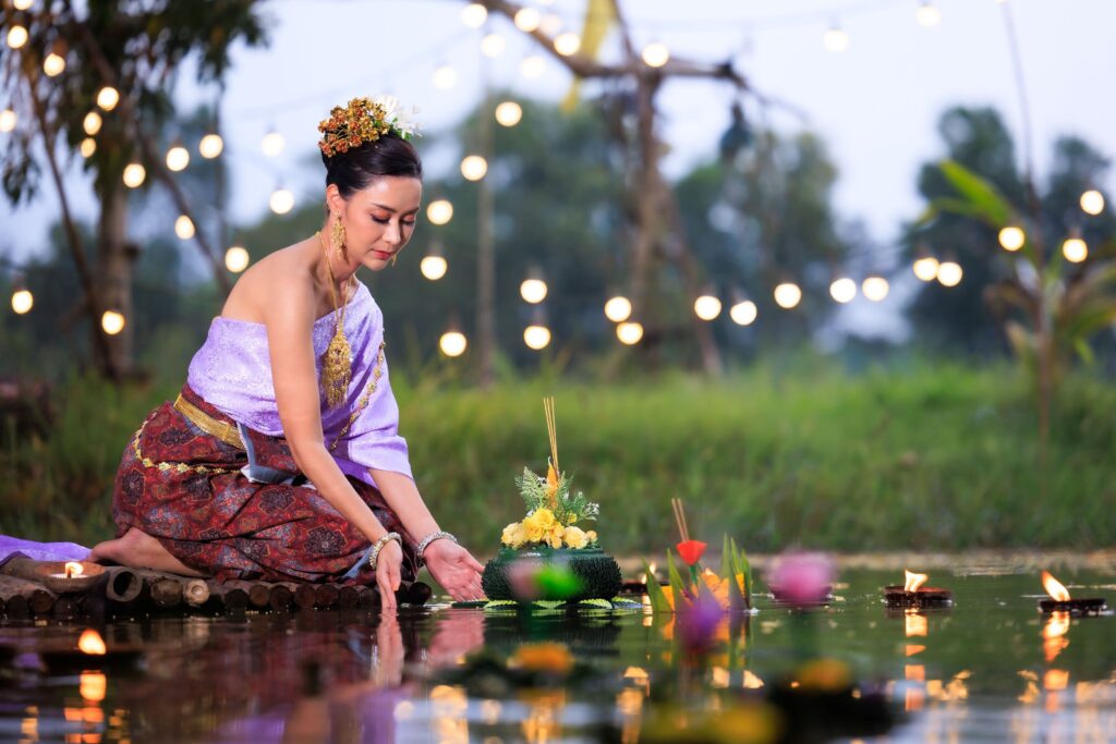 Eine thailändische Frau setzt ein Krathong ins Wasser